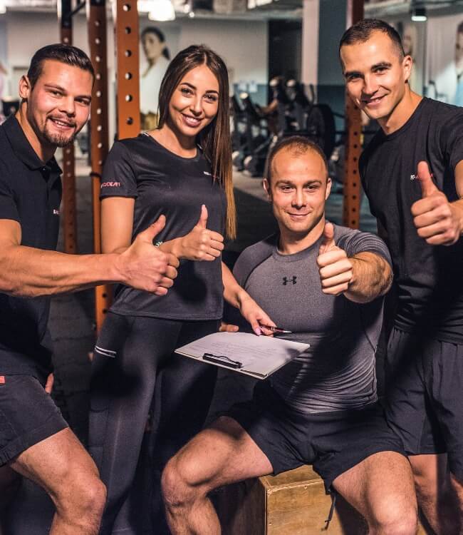 A team of professional fitness instructors giving a thumbs up after a successful training session.